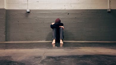 A person sitting alone in a corner, evoking themes of solitude and emotion.